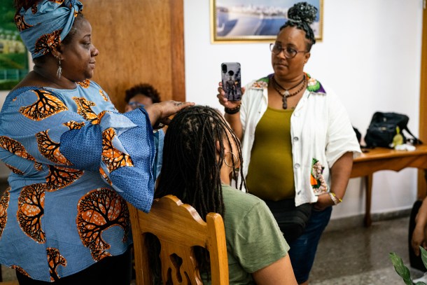 Sacramento loctician and salon owner Akilah Hatchett-Fall conducts a demo on fellow traveler Toya Dones’ locs while Afrodiverso member Oyantay records the session 